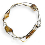 A handcrafted cuff bracelet featuring a mix of yellow opal, faceted citrine, banded agate, and hessonite raw crystal, wrapped in gold fill and set in among brass and oxidized sterling silver geometric cuff bracelet that's been stamped with trees