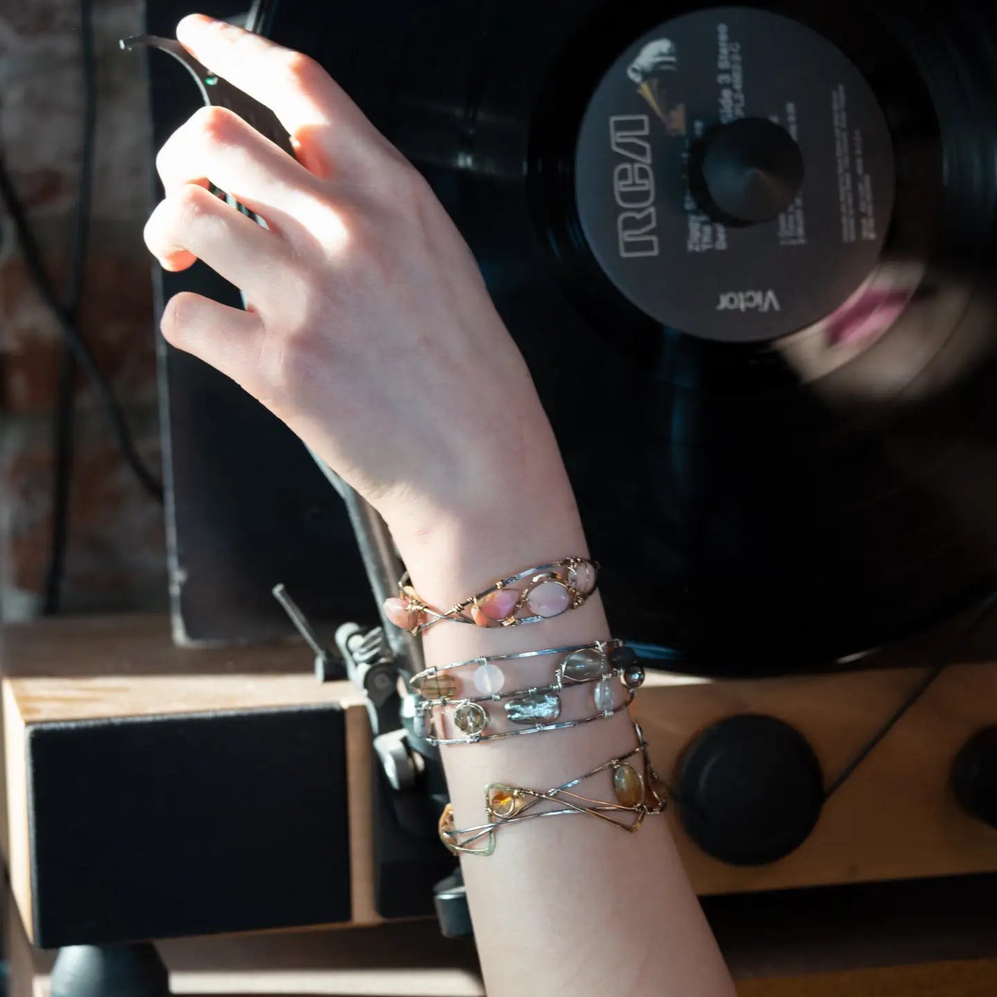 A handcrafted cuff bracelet featuring a mix of yellow opal, faceted citrine, banded agate, and hessonite raw crystal, wrapped in gold fill and set in among brass and oxidized sterling silver geometric cuff bracelet that's been stamped with trees