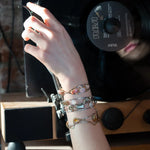 A handcrafted cuff bracelet featuring a mix of yellow opal, faceted citrine, banded agate, and hessonite raw crystal, wrapped in gold fill and set in among brass and oxidized sterling silver geometric cuff bracelet that's been stamped with trees