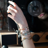 A handcrafted cuff bracelet featuring a mix of yellow opal, faceted citrine, banded agate, and hessonite raw crystal, wrapped in gold fill and set in among brass and oxidized sterling silver geometric cuff bracelet that's been stamped with trees