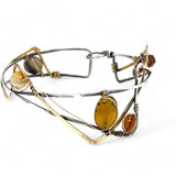 A handcrafted cuff bracelet featuring a mix of yellow opal, faceted citrine, banded agate, and hessonite raw crystal, wrapped in gold fill and set in among brass and oxidized sterling silver geometric cuff bracelet that's been stamped with trees