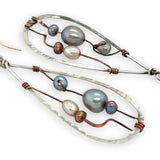 Variety of blue, purple, cream and rust fresh water pearls wrapped in hammered copper wire held onto a sterling silver drop earring