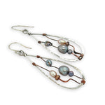 Variety of blue, purple, cream and rust fresh water pearls wrapped in hammered copper wire held onto a sterling silver drop earring