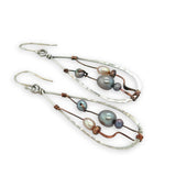 Variety of blue, purple, cream and rust fresh water pearls wrapped in hammered copper wire held onto a sterling silver drop earring