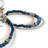 Blue crystal, sodalite, and rich blue quartz gemstones are set between bronze hammered drops and hammered oxidized sterling silver twist earrings