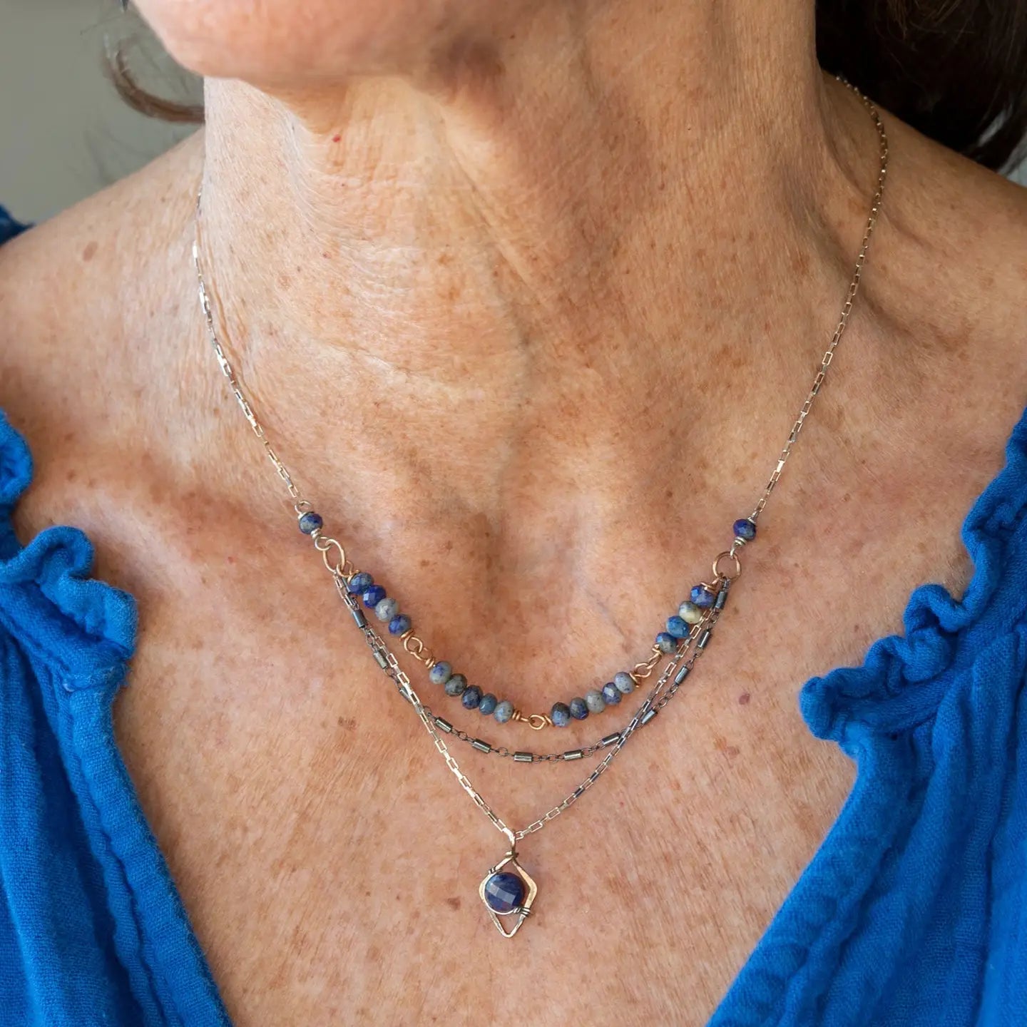 A sterling silver and bronze triple strand chain necklace with blue lapis and sodalite gemstones