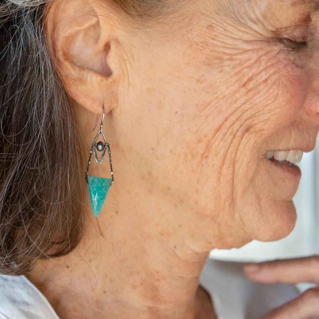 A pair of mini darkened diamonds with fresh water pearls with oxidized sterling silver dot chain holding a  a bright turquoise triangular gemstone earring
