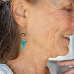 A pair of mini darkened diamonds with fresh water pearls with oxidized sterling silver dot chain holding a  a bright turquoise triangular gemstone earring