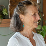 A pair of mini darkened diamonds with fresh water pearls with oxidized sterling silver dot chain holding a  a bright turquoise triangular gemstone earring