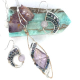 A necklace with a bronze marquise pendant featuring a ametyst center stone encrusted with ruby zoisite, fresh water pearl, and sodalite gemstones with sterling silver wire accent