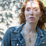 A necklace with a bronze marquise pendant featuring a ametyst center stone encrusted with ruby zoisite, fresh water pearl, and sodalite gemstones with sterling silver wire accent