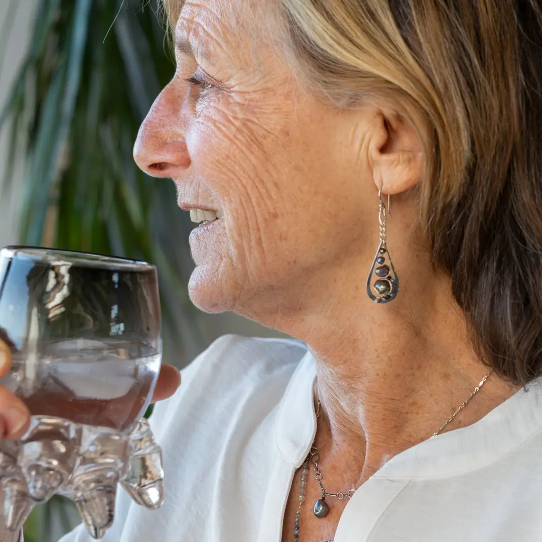 A pair of sterling silver teardrop earrings hang from curb link chain with blue/purple fresh water pearls and sodalite gemstone accents