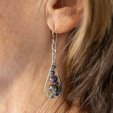 A pair of sterling silver teardrop earrings hang from curb link chain with blue/purple fresh water pearls and sodalite gemstone accents