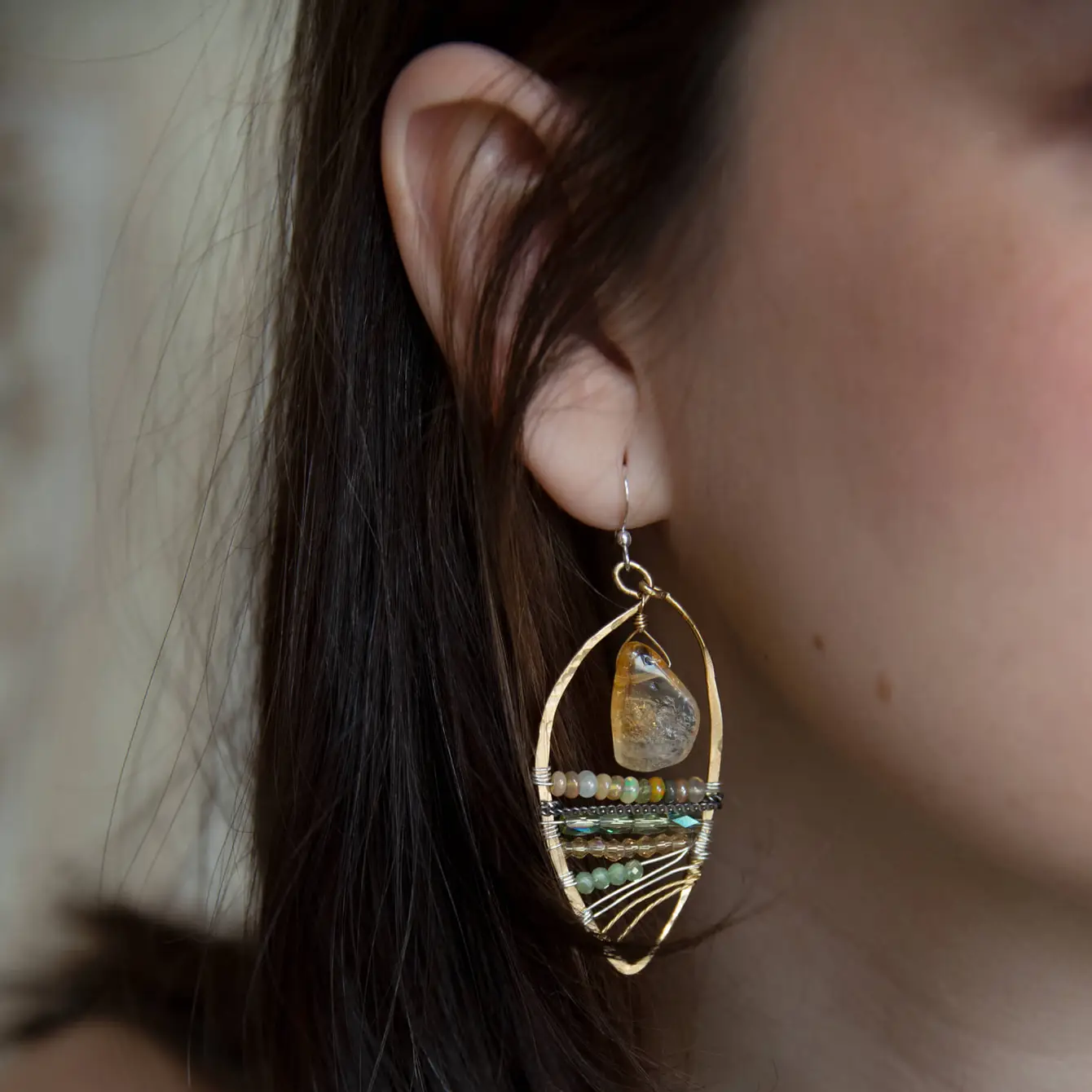 Smooth citrine nuggets hang above layers of green and orange crystal and luminescent citrine gemstones within a handmade hammered brass drop earrings