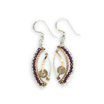 Pair of earrings with gold and silver loops and garnet beads on a white background