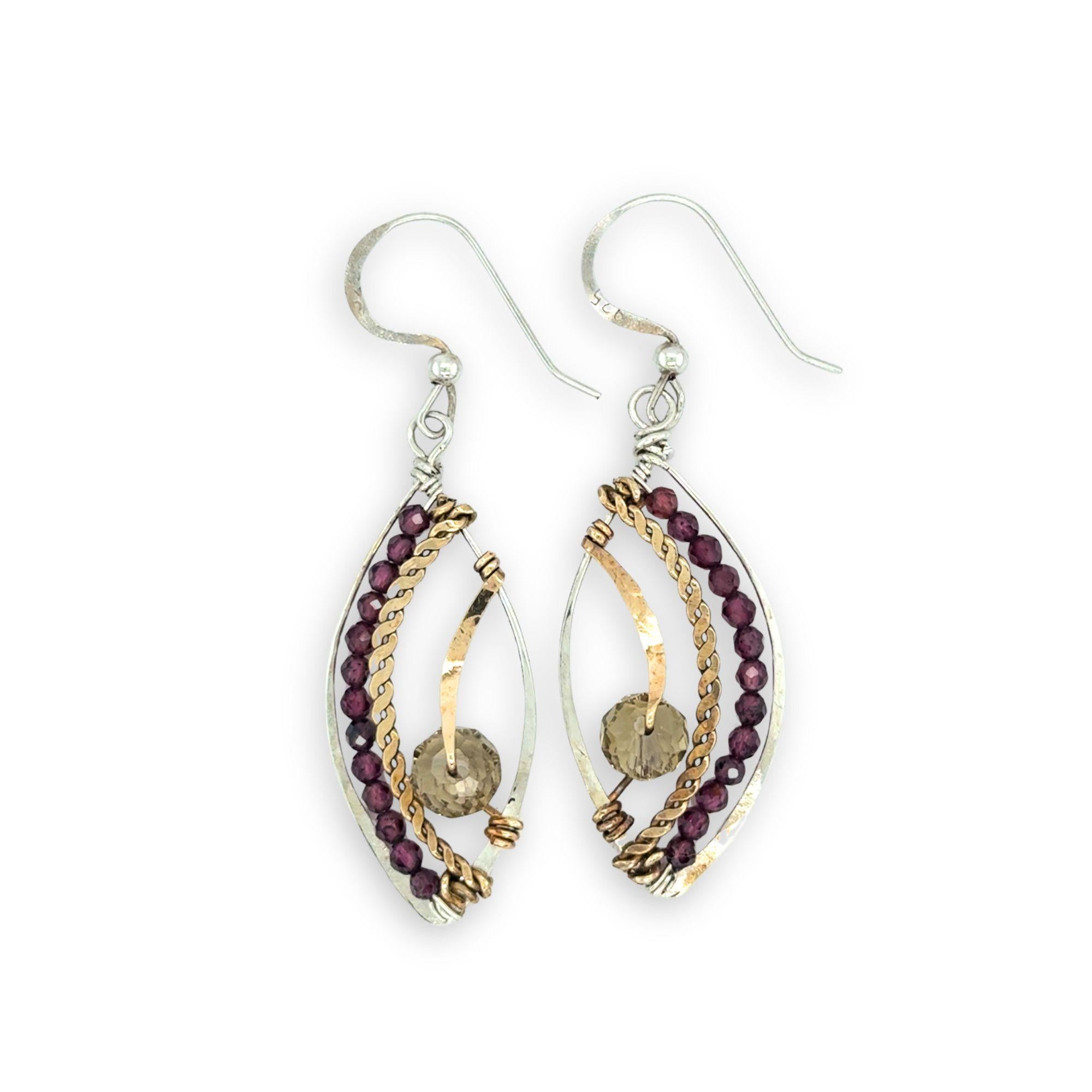 Pair of earrings with gold and silver loops and garnet beads on a white background
