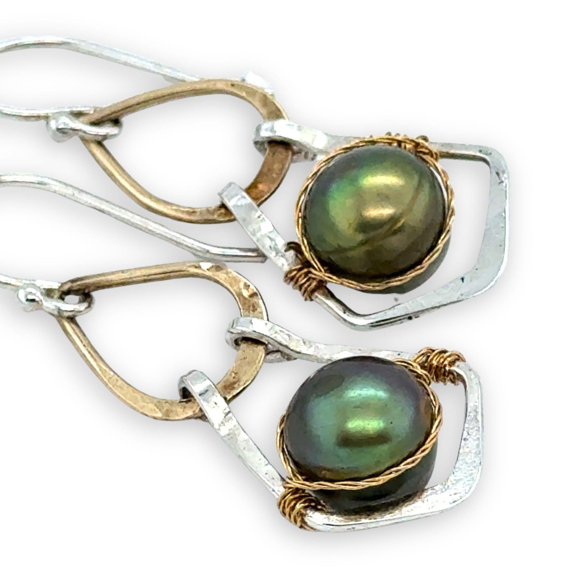 Pair of earrings with green pearls and gold and silver wirework on a white background