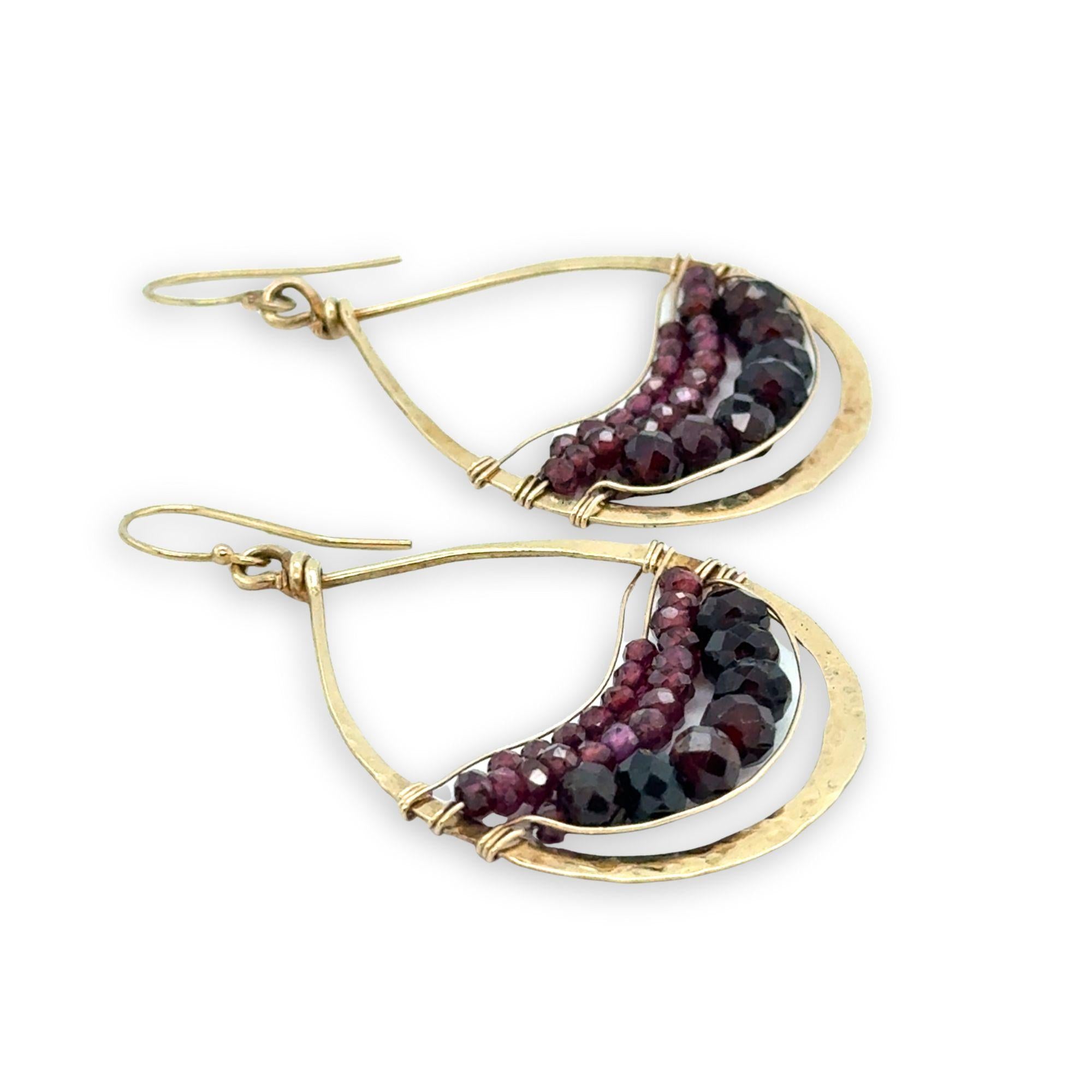 Gold earrings with garnet gemstones on a white background