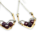 Two gold and silver earrings with garnet stones on a white background