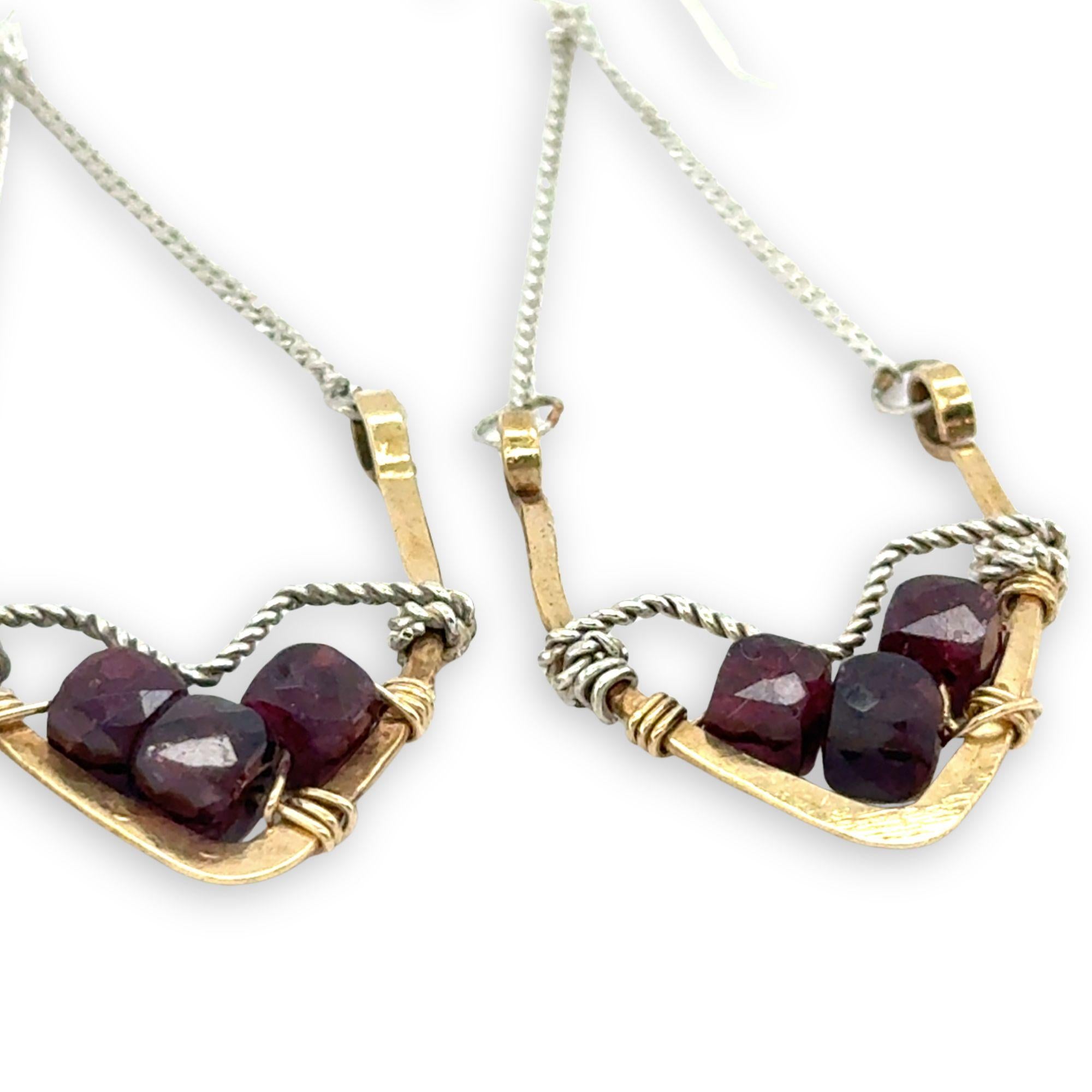 Two gold and silver earrings with garnet stones on a white background