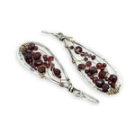 Teardrop-shaped earrings with garnet beads and gold wirework on a white background