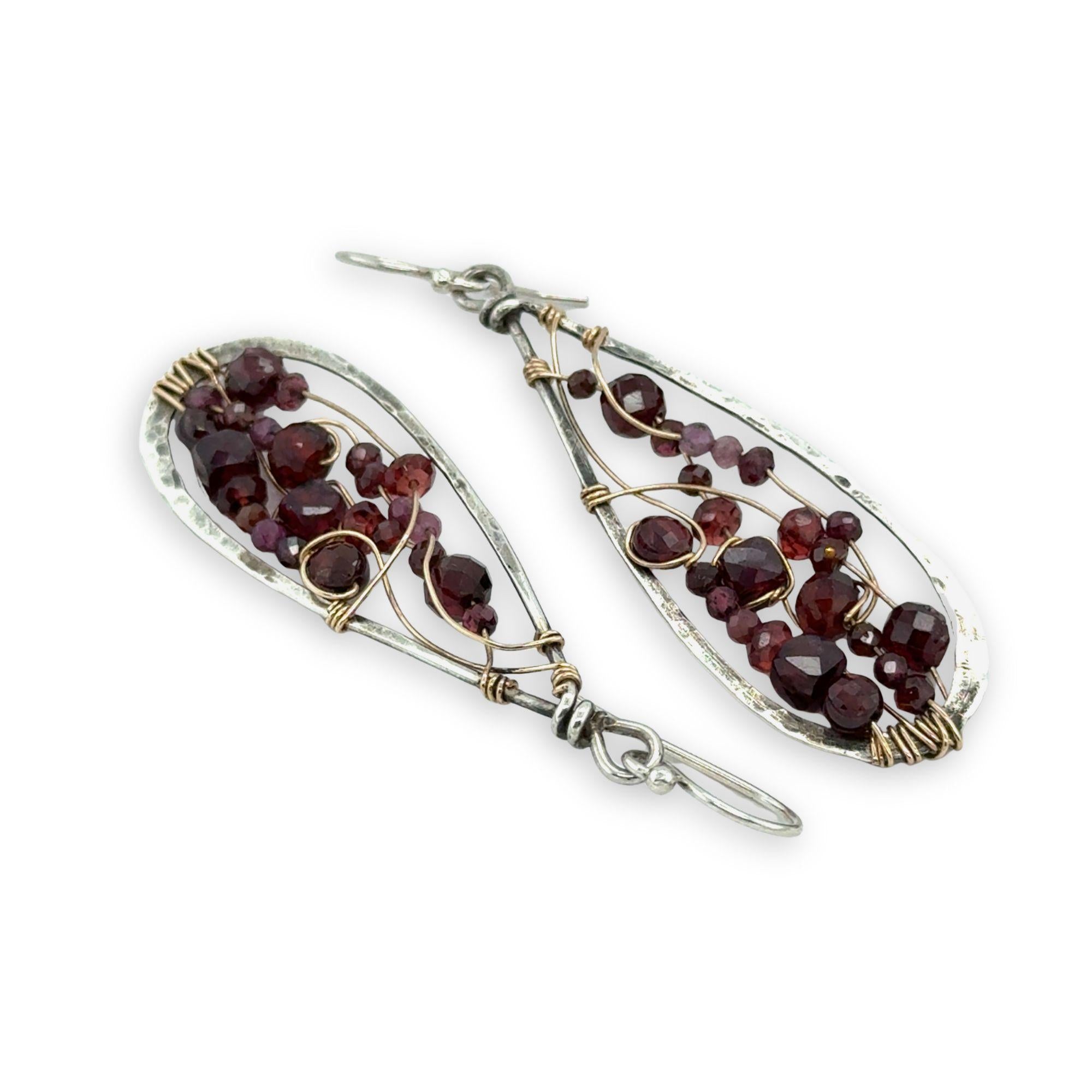 Teardrop-shaped earrings with garnet beads and gold wirework on a white background