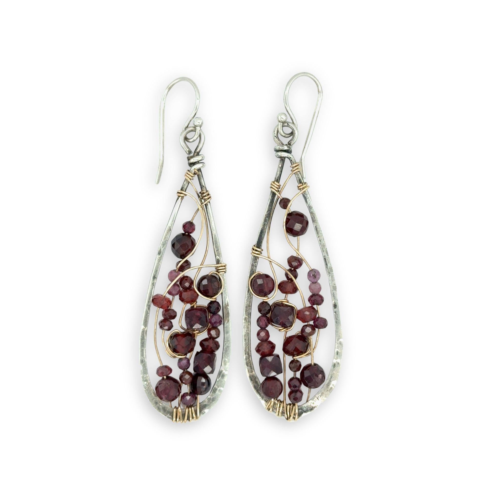 Teardrop-shaped earrings with garnet beads and gold wirework on a white background