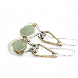 Pair of earrings with green jade gemstones and gold and silver hooks on a white background