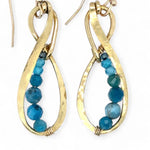 Gold earrings with apatite gemstone beads on a white background
