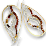 A pair of large teardrop-shaped earrings with gold-tone outer frames, layered silver-tone wire, and strands of small beads in brown, reddish-brown, cream, and amber tones, shown on a white background.