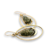 A pair of gold dangle earrings featuring organic-shaped gold wire loops and oval bezel settings holding dark green marbled stone beads, shown on a white background.