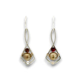 A pair of silver dangle earrings featuring a large round freshwater pearl, a small round red gemstone, and a tiny clear crystal, shown on a white background.