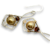 A pair of handmade dangle earrings featuring large round brown freshwater pearls, wrapped in silver and gold wire with small accent beads, on a white background.