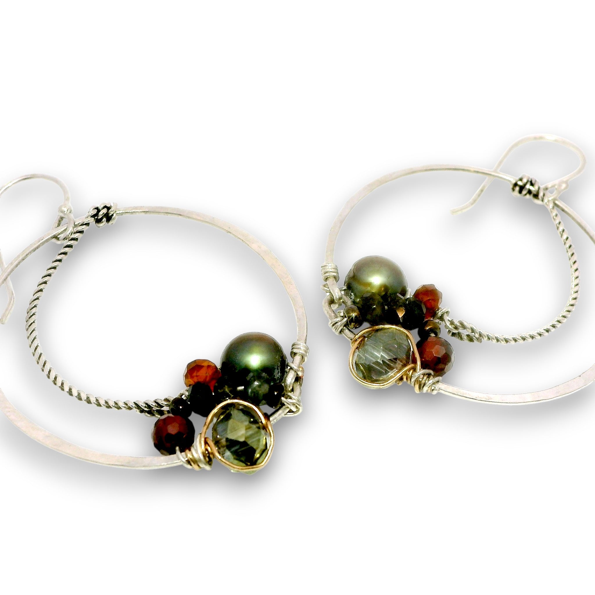 A pair of handmade silver hoop earrings with twisted wire details, featuring green and dark red beads, set against a plain white background.