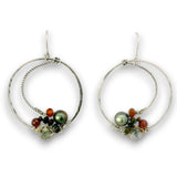 A pair of silver hoop earrings with textured and twisted wire details, decorated with green and black pearls, small orange beads, and clear faceted beads on a white background.