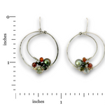 A pair of silver hoop earrings with small gemstone clusters, shown on a white background with inch measurement markers. The earrings feature textured and twisted silver hoops with a cluster of beads at the bottom, including a dark green freshwater pearl, orange and black beads, and a light green stone.