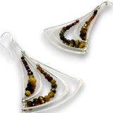 A pair of silver dangle earrings with layered triangular wire frames and rows of faceted brown, amber, and black beads, shown on a white background.