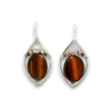 A pair of silver-toned teardrop dangle earrings featuring a large oval brown tiger's eye stone in the center, accented with small pink and clear crystals, shown on a white background.
