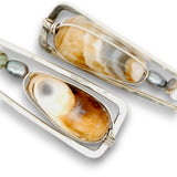 Two silver-toned rectangular pendant necklaces with large teardrop-shaped natural shell inlays in cream, tan, and brown, accented with small dark gray pearls, shown on a white background.
