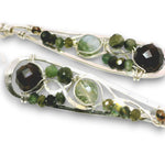 Two silver-toned wire-wrapped earrings with green and dark brown gemstone accents, displayed on a clean white background.