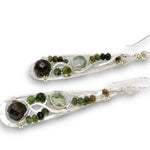 A pair of silver teardrop-shaped dangle earrings featuring green and brown gemstone beads and small round green beads, shown on a plain white background.