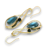 A pair of gold dangle earrings featuring large teardrop-shaped blue-green labradorite stones, small dark round gemstones, and tiny dark green faceted beads, set against a plain white background.