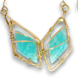 A gold butterfly-shaped pendant necklace featuring two large, textured light turquoise-blue gemstone wings wrapped in thin gold wire, shown against a plain white background.