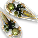 A pair of teardrop-shaped earrings featuring olive green freshwater pearls, faceted green beads, clear crystal points, and silver and gold wire wrapping on a white background.