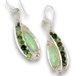 A pair of silver and gold wire-wrapped dangle earrings featuring oval-cut light green gemstone centers and a row of faceted green beads, shown on a white background.
