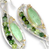 A pair of handmade dangle earrings featuring polished light green aventurine gemstone centers, accented with faceted green beads and small gold wire wraps, suspended from hammered silver-toned metal frames.