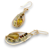 A pair of gold drop earrings featuring a large teardrop-shaped yellow gemstone, accented with small round beads in green, white, and brown, set in a textured gold frame on a white background.