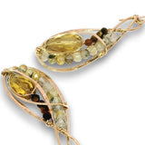 A pair of gold and rose gold wire-wrapped earrings featuring large oval-cut yellow gemstones and rows of small multicolored beads, shown on a white background.