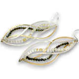A pair of leaf-shaped dangle earrings featuring twisted gold and silver-tone metal wires, accented with strands of small faceted beads in olive green, dark brown, and milky white, shown on a plain white background.