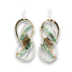 A pair of dangling earrings with a twisted infinity design, featuring green bead strands, a brown smoky quartz center stone, and silver and gold wire wrapping on a white background.